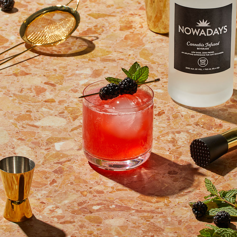 Nowadays Bramble On Edible Drink with berry garnish on textured counter top