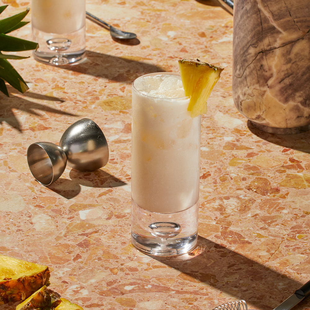 Nowadays Colada Livin' THC Infused Cocktail with pineapple on textured counter top